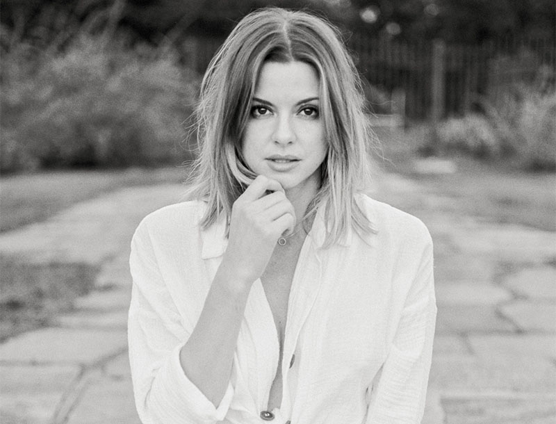 Schwarz-Weiß-Porträt einer Frau, die ihre Hand ans Kinn hält.